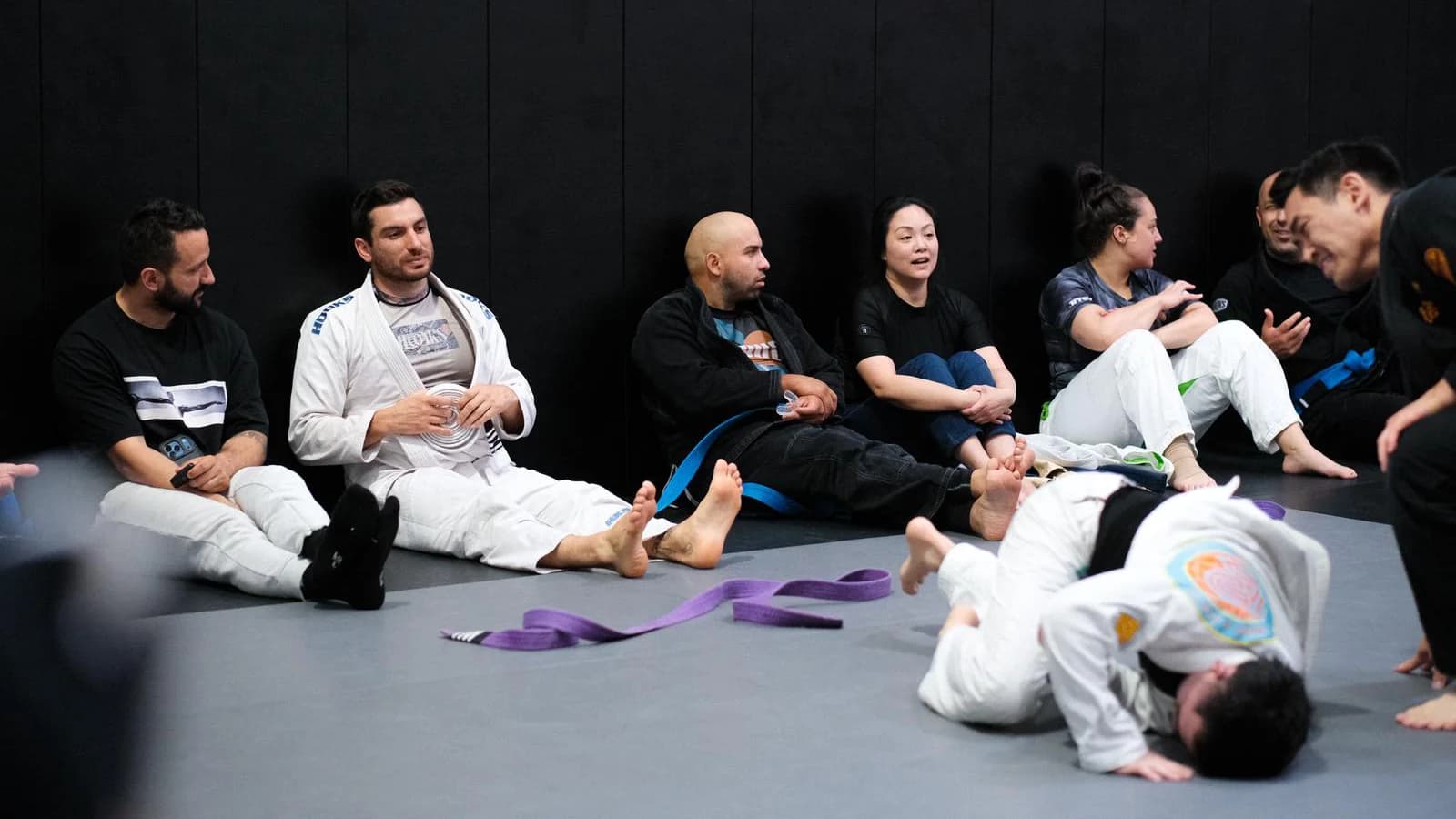Martial arts students training together in a supportive gym environment
